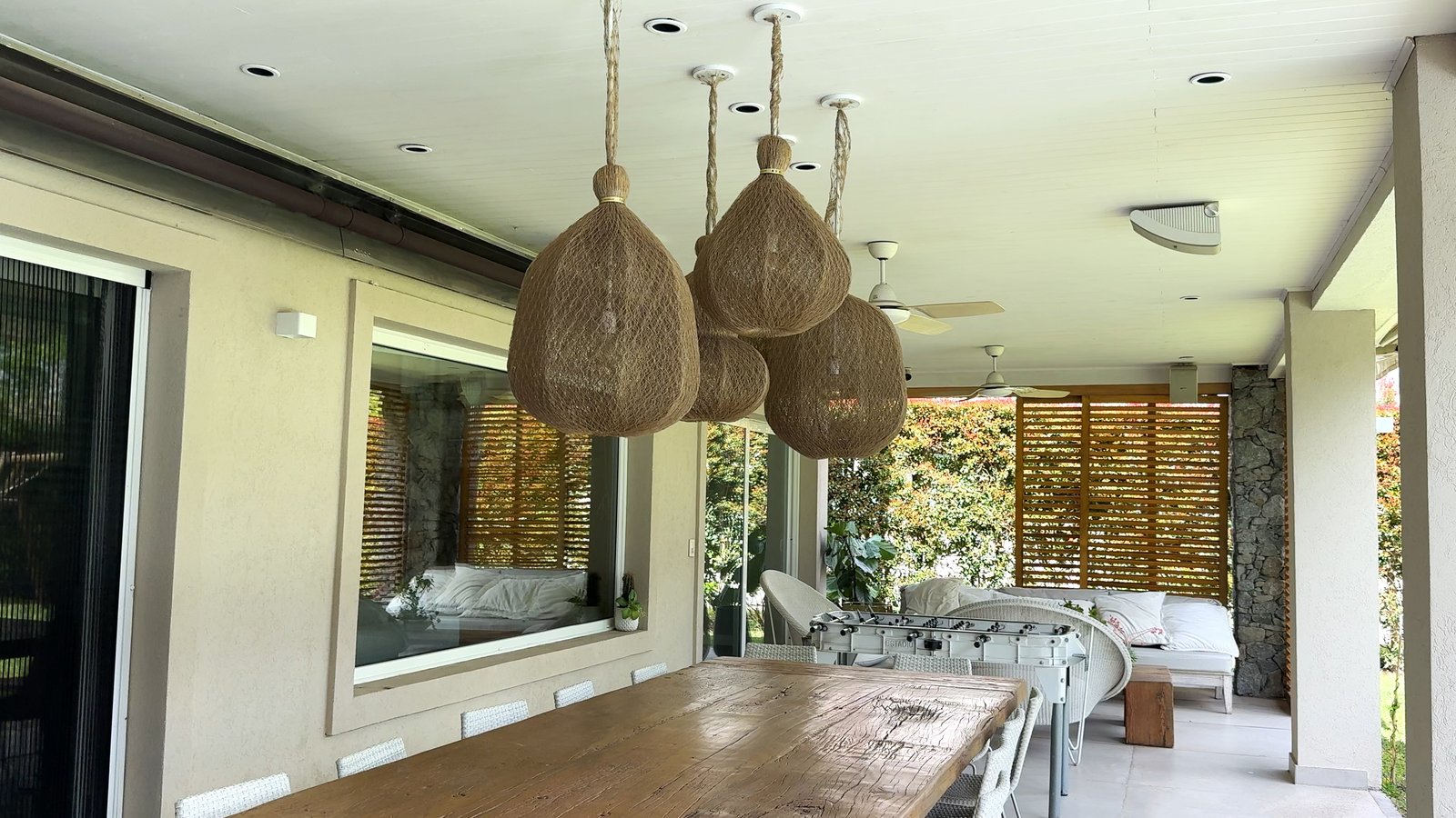 Sala de jantar semi-externa rústica com mesa longa e cadeiras de vime — projeto CASA CM, por Hermann Arquitectos, em Los Castores